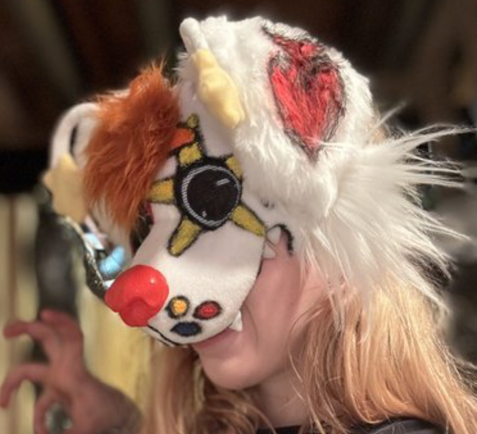 White clown creature mask with a red nose being worn